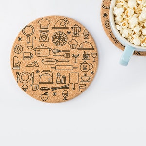 May include: A round cork coaster featuring a design of various kitchen icons in black outlines. The coaster is on a white surface.