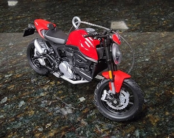 May include: A red motorcycle with black wheels and a silver exhaust pipe. The motorcycle is on a dark gray surface.