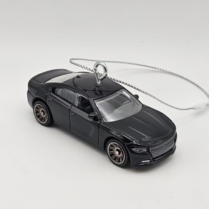 May include: Black Dodge Charger car ornament with a silver string for hanging.
