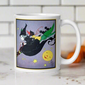 May include: White ceramic mug featuring a colourful illustration of a witch flying on a broomstick with three black cats. The witch is wearing a black dress and a pointed hat. The background is a purple sky with stars and a yellow moon with a smiling face.