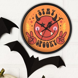 May include: A black and orange Halloween clock with a red devil face and the text "Stay Spooky". The clock is surrounded by bats and pumpkins.