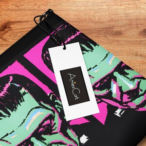 May include: Black and pink zippered pouch with a graphic print of two green and black Frankenstein-like faces. The pouch has a black tag attached with the text "AriesCat" in white.