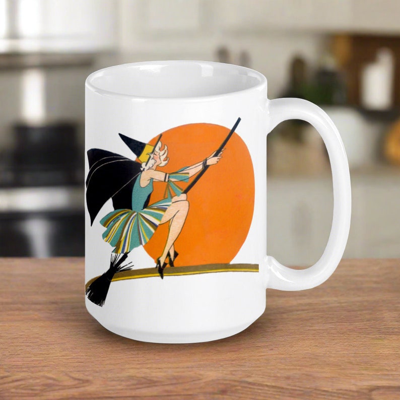 This ceramic coffee mug features a vintage deco illustration of a cute flapper witch flying on a broom with an orange full moon behind her.