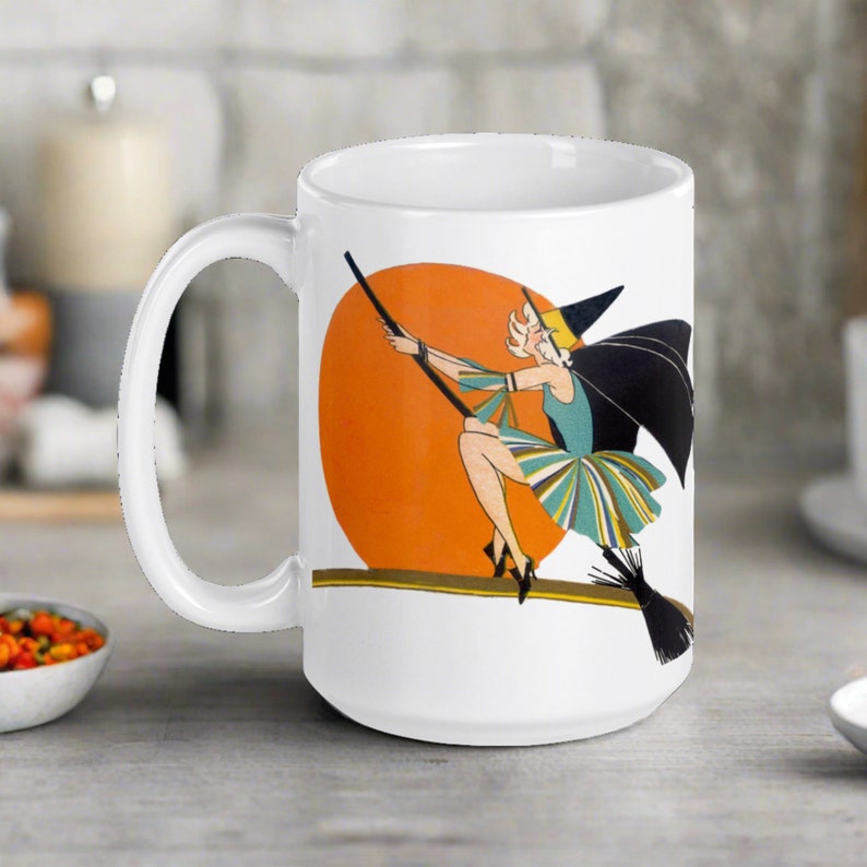 This ceramic coffee mug features a vintage deco illustration of a cute flapper witch flying on a broom with an orange full moon behind her.
