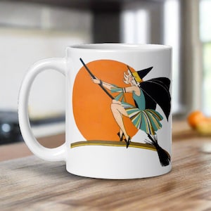 This ceramic coffee mug features a vintage deco illustration of a cute flapper witch flying on a broom with an orange full moon behind her.