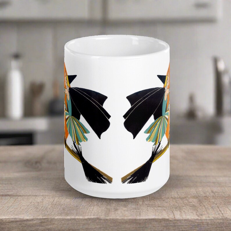 This ceramic coffee mug features a vintage deco illustration of a cute flapper witch flying on a broom with an orange full moon behind her.