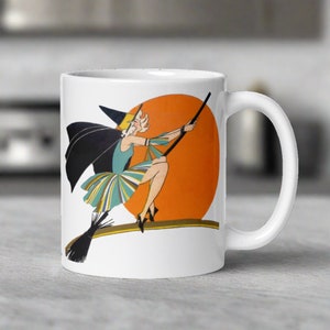 This ceramic coffee mug features a vintage deco illustration of a cute flapper witch flying on a broom with an orange full moon behind her.