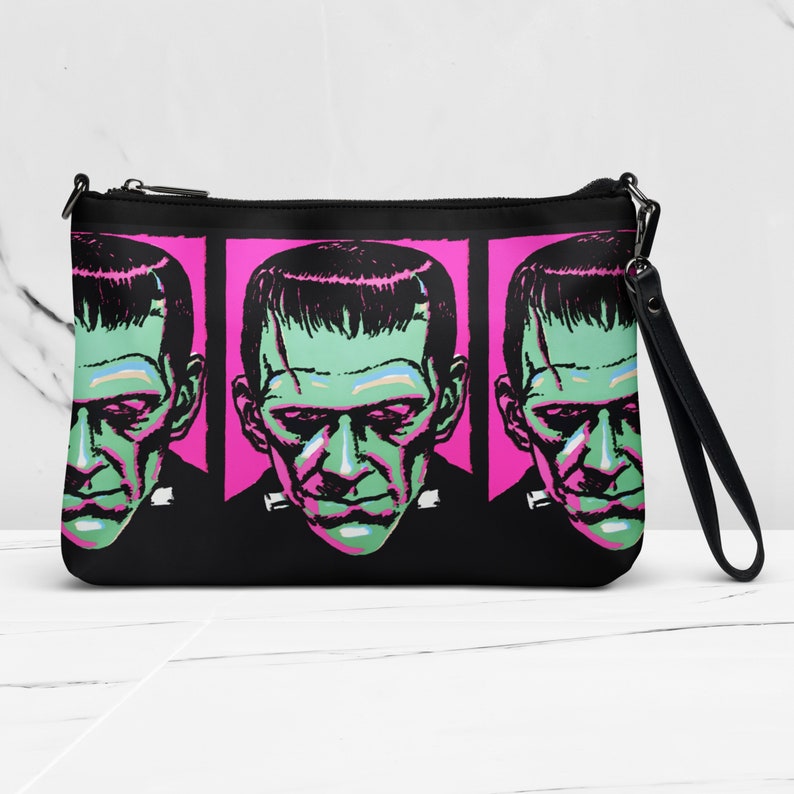 May include: Black clutch bag with a pink background and a repeating pattern of green and black Frankenstein's monster faces.