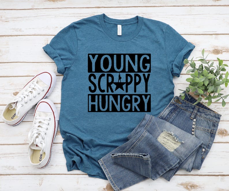 May include: A teal blue t-shirt with the text "Young, Scrappy, Hungry" in black lettering. The shirt has a star in the middle of the text.