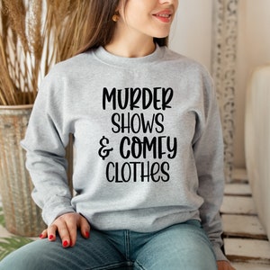 May include: A gray sweatshirt with the text "Murder Shows & Comfy Clothes" printed in black.