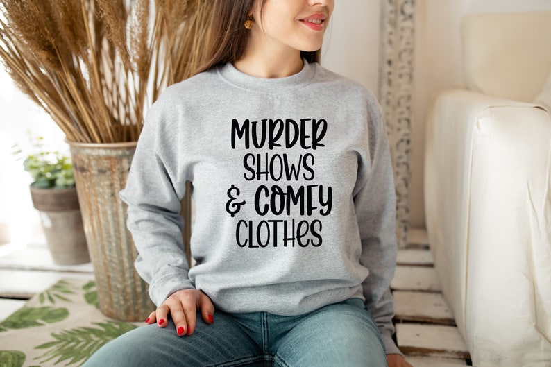 May include: A gray sweatshirt with the text "Murder Shows & Comfy Clothes" printed in black.