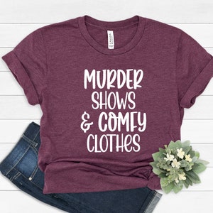 May include: Burgundy t-shirt with white text that reads "Murder Shows & Comfy Clothes".