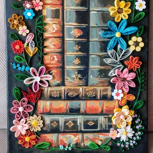May include: A canvas painting depicting a stack of books against a dark backdrop. The books are rendered in shades of brown and blue. The artwork is adorned with colourful paper flowers in yellow, pink, red, and blue, creating a decorative border.