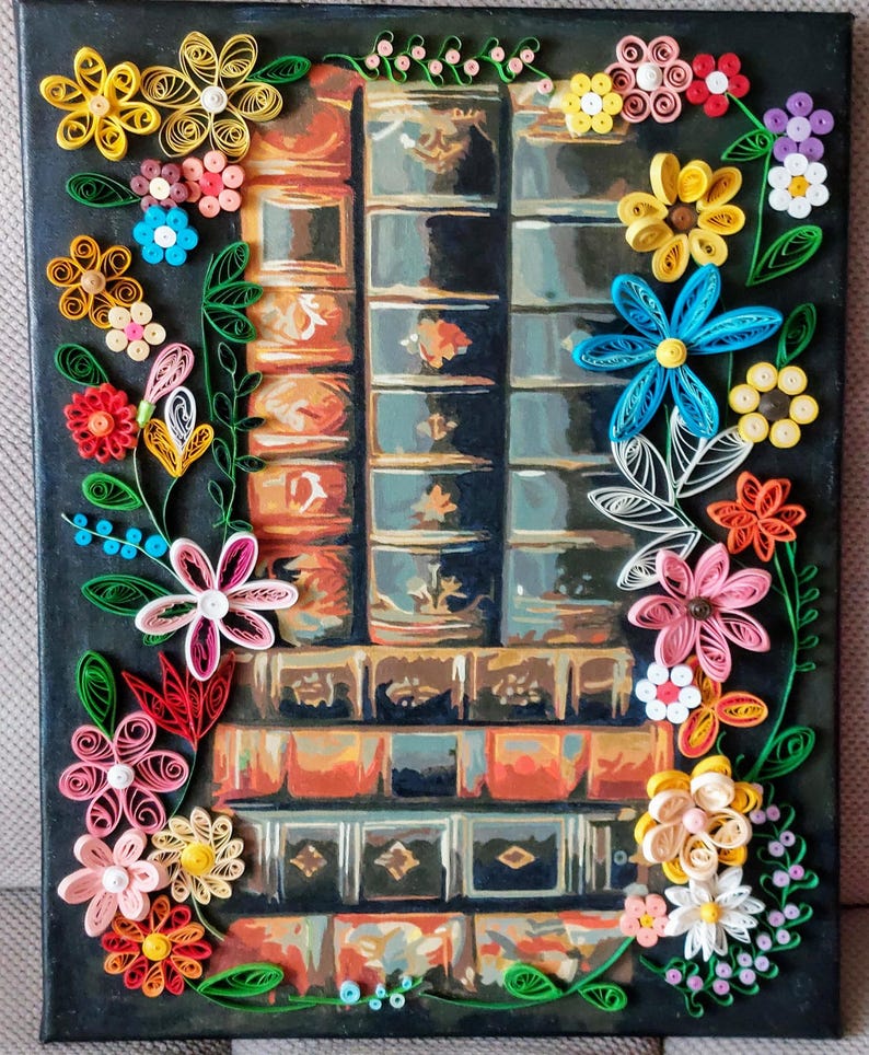 May include: A canvas painting depicting a stack of books against a dark backdrop. The books are rendered in shades of brown and blue. The artwork is adorned with colourful paper flowers in yellow, pink, red, and blue, creating a decorative border.