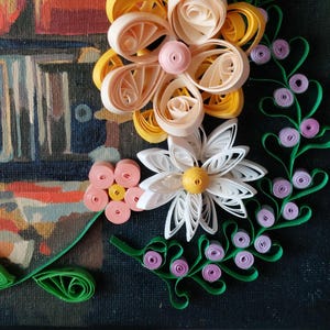 May include: A detailed paper quilling artwork with a floral theme. The piece showcases white, yellow, and pink paper flowers, green vines, and purple berries. The background is a dark canvas with a blurred painting.
