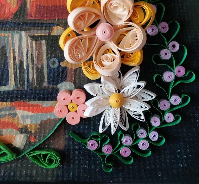May include: A detailed paper quilling artwork with a floral theme. The piece showcases white, yellow, and pink paper flowers, green vines, and purple berries. The background is a dark canvas with a blurred painting.