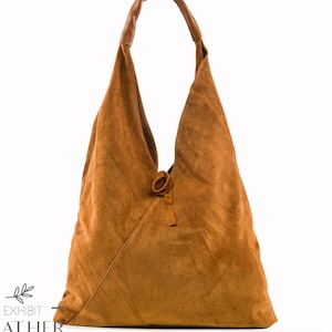 May include: A brown suede hobo bag with a knotted strap. The bag has a triangular shape and is made of soft, supple leather.
