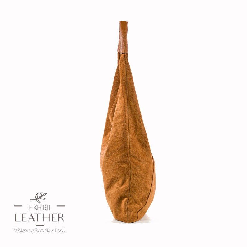 May include: A brown leather tote bag with a brown leather handle. The bag is made of a soft, suede-like material.