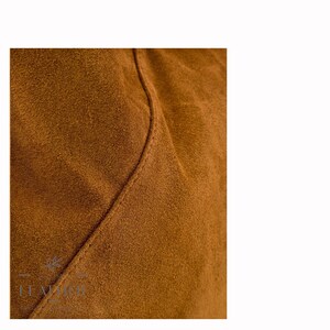 May include: Close-up of a brown suede fabric with a seam running diagonally across the surface.