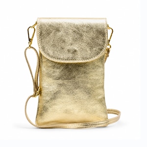 May include: A gold-coloured crossbody bag with a flap closure and a detachable shoulder strap. The bag has a textured surface and gold-toned hardware, including a clasp and strap attachments. The bag is designed to hold a phone and other small items.