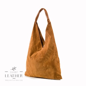 May include: A brown suede hobo bag with a brown leather handle. The bag has a triangular shape and is made of soft, supple suede.
