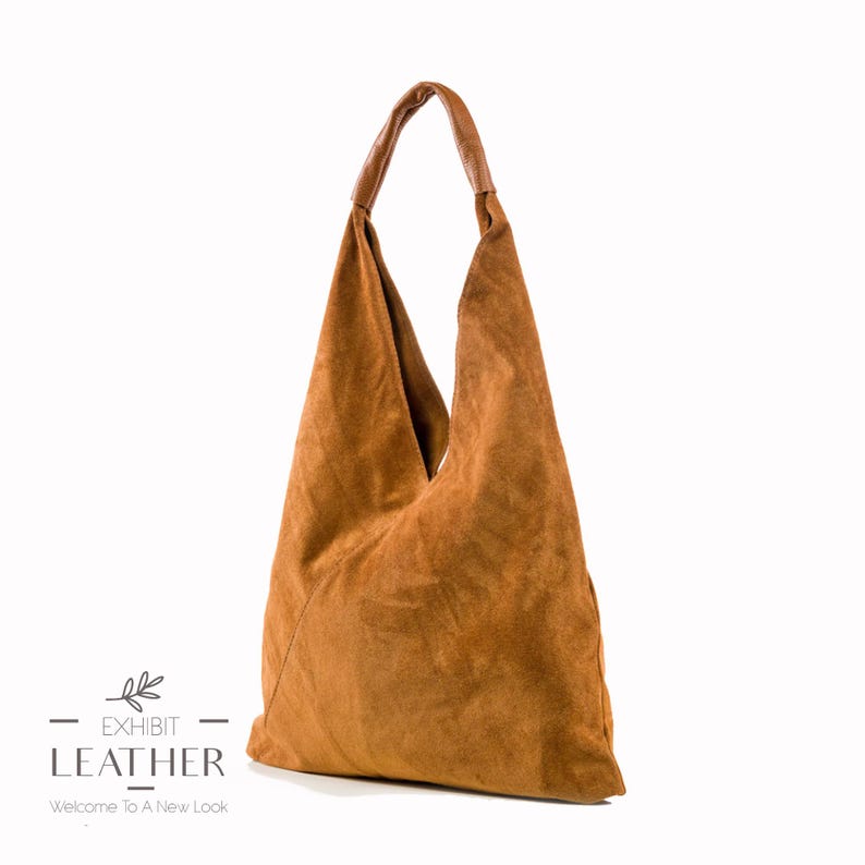 May include: A brown suede hobo bag with a brown leather handle. The bag has a triangular shape and is made of soft, supple suede.