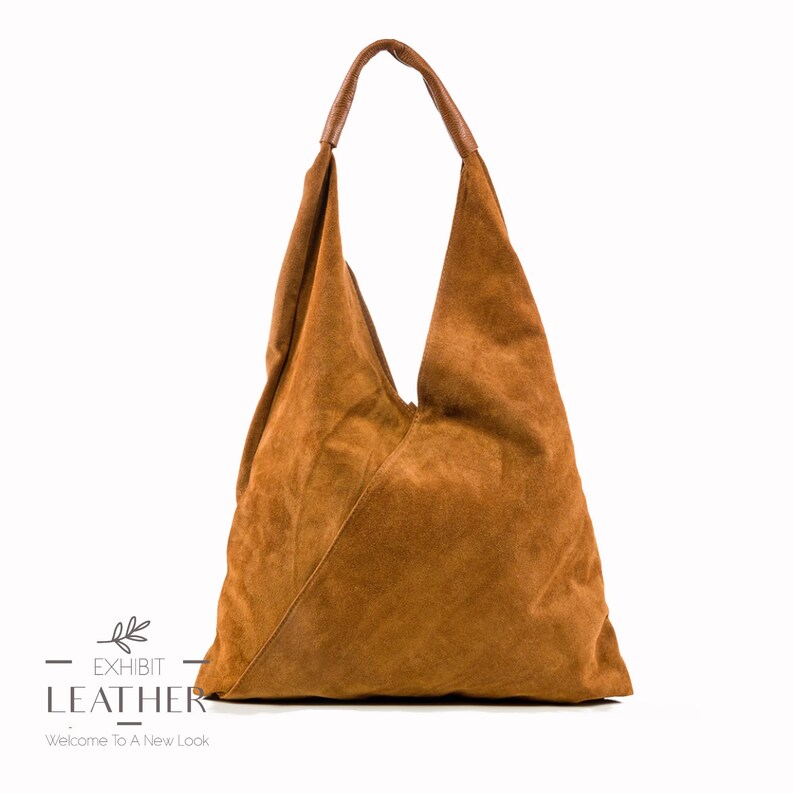 May include: A brown suede tote bag with a triangular shape and a single strap. The bag has a simple design and is made of soft, supple leather.