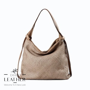 Puede incluir: Bolso de hombro de cuero tejido beige con una correa larga. El bolso tiene un diseño holgado y una textura tejida. El bolso tiene el texto "EXHIBIT LEATHER" y "Welcome To A New Look" en la esquina inferior izquierda.