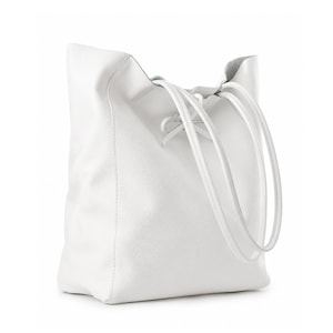 Pode incluir: Uma bolsa tote branca com superf&iacute;cie texturizada e silhueta macia e desestruturada. A bolsa possui duas al&ccedil;as de ombro longas e finas e um fecho de cord&atilde;o na parte superior central que se amarra em um pequeno la&ccedil;o, criando uma abertura.