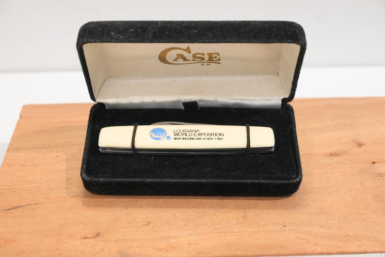May include: A vintage Case XX pocket knife in a black velvet presentation box. The knife has a cream-colored handle with black accents and text that reads "Louisiana World Exposition New Orleans May 12-Nov 11 1984."