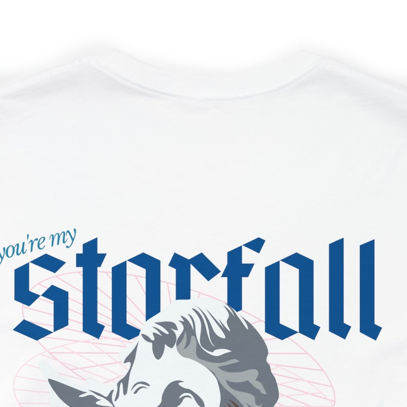 May include: White t-shirt with a blue graphic that says "you're my starfall" in a gothic font. A white and gray sculpture of a woman's head is partially visible below the text.