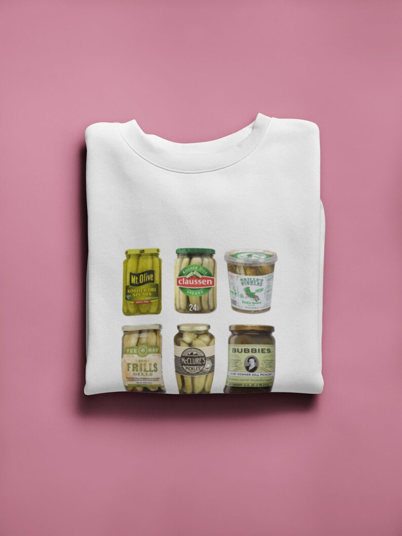 Peut inclure: Un t-shirt blanc avec un motif de six bocaux de cornichons diff&eacute;rents. Les bocaux sont &eacute;tiquet&eacute;s "Mr. Olive", "Claussen", "Gherkin Star", "Tee-Hee", "McClure's" et "Bubbie's".