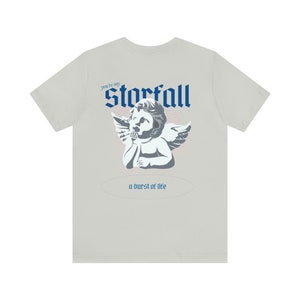 May include: A light gray t-shirt with a blue and white graphic of an angel with the text "You're my Starfall a burst of life" printed on the back.