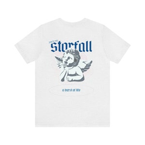 May include: White t-shirt with a blue and gray graphic of a cherub with wings. The text "You're my Storfall" and "a burst of life" are printed on the shirt.