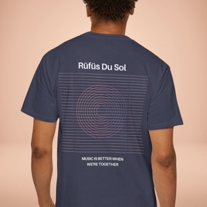 May include: A navy blue t-shirt with a white graphic design on the back. The graphic features a circle with concentric rings and the text "RÜFÜS DU SOL" and "MUSIC IS BETTER WHEN WE'RE TOGETHER".