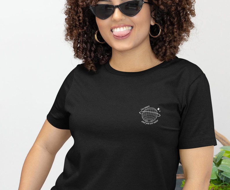 May include: A black t-shirt with a white graphic of a globe with the text "The world is yours and you are here".