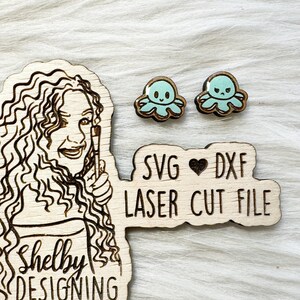 May include: Wooden laser cut file set featuring a woman's portrait, two octopus earrings, and text that reads "SVG, DXF, LASER CUT FILE". The earrings have a light blue octopus design with a brown border. The woman's portrait is a line drawing.