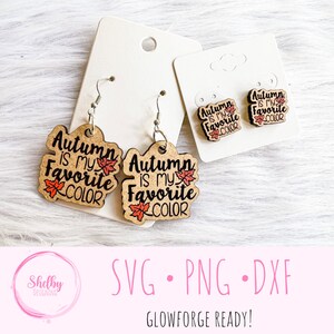 May include: A pair of wooden earrings with the text "Autumn is my favorite color" and a small orange leaf design. The earrings are on a white background.