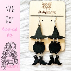 May include: Black witch hat, cauldron, and boot dangle earrings. The earrings are on a wooden display stand with the text "ShelbyDESIGNING".