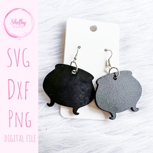 Puede incluir: Un par de pendientes de caldero negro con ganchos plateados. Los pendientes están sobre un fondo blanco.