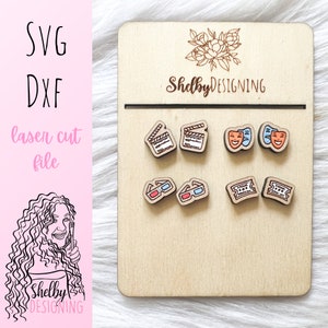 May include: A set of six wooden earrings with movie-themed designs. The earrings feature a clapperboard, two theater masks, 3D glasses, and two movie tickets. The earrings are displayed on a wooden board with the text "Shelby DESIGNING" printed on it.