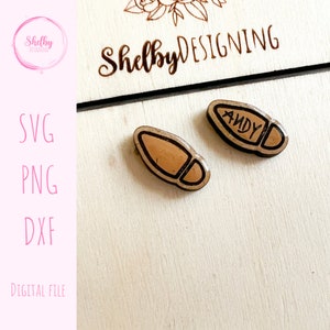 May include: Two small, wooden shoe-shaped ornaments with a brown interior and black outline. One ornament has the name "ANDY" written on it. The image also includes the text "Shelby DESIGNING", "SVG", "PNG", "DXF", and "DIGITAL FILE".
