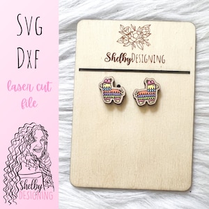 May include: A pair of wooden earrings featuring a colorful llama pinata design. The earrings are displayed on a wooden card with the text "Shelby DESIGNING".