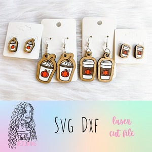 May include: Three sets of laser cut wooden earrings featuring fall-themed designs. The first set features a pumpkin spice latte with whipped cream, the second set features a pumpkin spice latte with whipped cream, and the third set features a coffee cup with a pumpkin on it. The earrings are on white card stock.