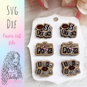 May include: Six wooden laser cut earrings with Mean Girls quotes. The earrings feature the phrases "So Fetch", "On Wednesdays We Wear Pink", and "Burn Book".