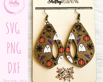 May include: A pair of wooden dangle earrings with a Halloween theme. The earrings are shaped like teardrops and feature a brown background with white ghosts, orange pumpkins, purple bats, and black spiderwebs.
