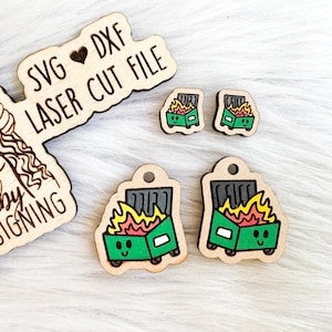 May include: Four laser cut wooden earrings featuring a green dumpster with a smiling face and orange flames. The earrings are labelled "SVG DXF LASER CUT FILE" and "Shelby Designing".