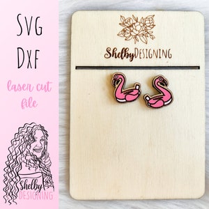 Könnte beinhalten: Ein Paar rosafarbene, flamingo-förmige Ohrringe aus Holz. Die Ohrringe sind lasergeschnitten und haben eine Holzmaserung. Die Ohrringe werden auf einem Holzbrett mit dem aufgedruckten Text "Shelby DESIGNING" präsentiert.