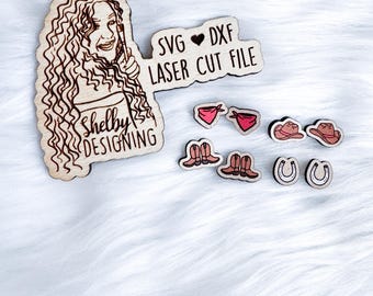 May include: A wooden cutout of a woman with curly hair, holding a paintbrush, with the text "Shelby Designing" below. The cutout is surrounded by smaller wooden cutouts of a cowboy hat, boots, a horseshoe, and a bandana. The text "SVG ♥ DXF LASER CUT FILE" is also included.