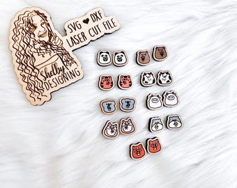 May include: A set of 12 laser cut wooden earrings featuring various animal designs, including koalas, pigs, and bears. The earrings are in shades of brown, grey, and red. The earrings are displayed on a white surface with a wooden sign that reads "SVG ♥ DXF LASER CUT FILE" and "Shelly Designing".